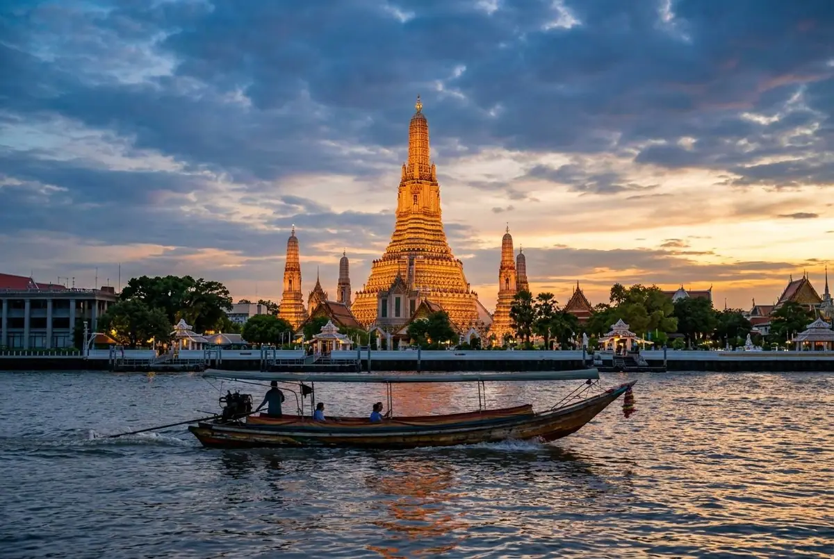 Wat Arun temple on the Chao Phraya River in Bangkok at sunset with a river boat passing