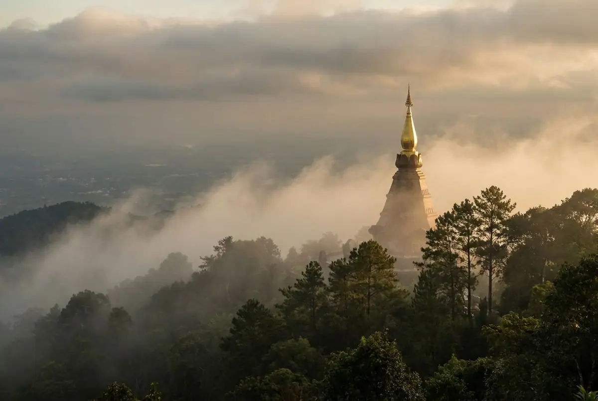 Misty mountains and a golden chedi above Chiang Mai in northern Thailand in early morning light