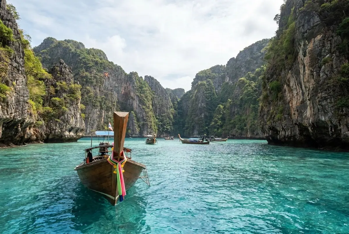 Limestone islands rising from clear turquoise water in the Andaman Sea near Phuket and Krabi with a long-tail boat